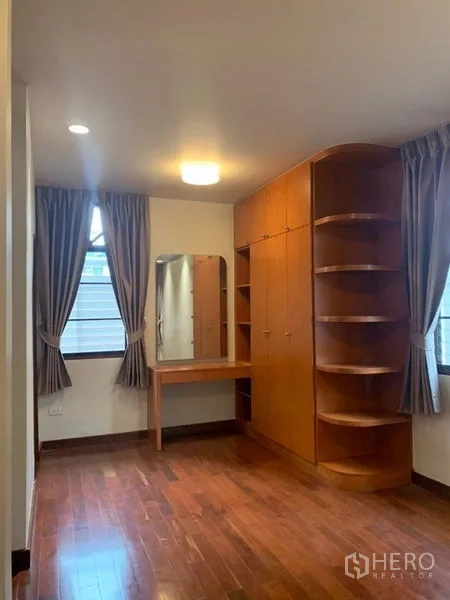 独立式住宅 出租在Ratchathewi, Bangkok - 卧室配内置木衣柜、梳妆台与木地板。