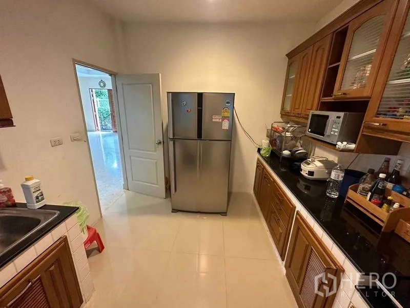 独立式住宅 出售在Saphan Sung, Bangkok - 封闭式厨房，木质橱柜、黑色台面与不锈钢冰箱。