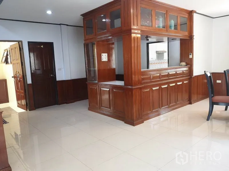 Detached House for sale - Living area with glossy tile floors and a tall built-in wooden partition cabinet.