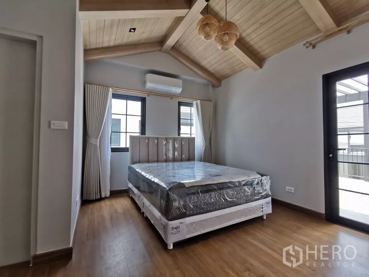 Detached House for rent in Bang Phli, Samut Prakan - Bedroom with vaulted wooden ceiling and a door opening to the balcony.