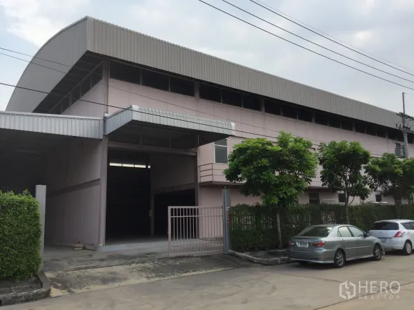 โรงงาน ให้เช่าในLam Luk Ka, Pathum Thani - อาคารโรงงานสีชมพูพร้อมประตูม้วน ทางเข้าและที่จอดรถในโครงการ
