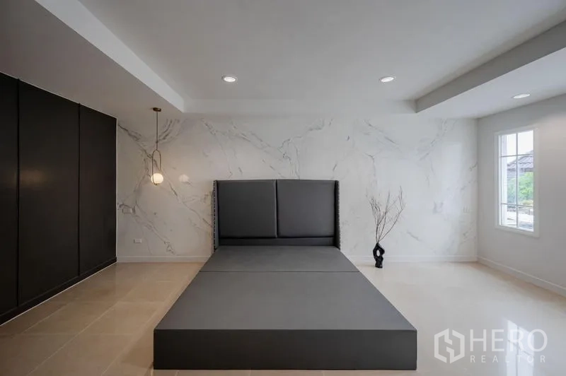 Townhouse for sale - Spacious bedroom with marble-effect accent wall, platform bed and built-in dark wardrobe.