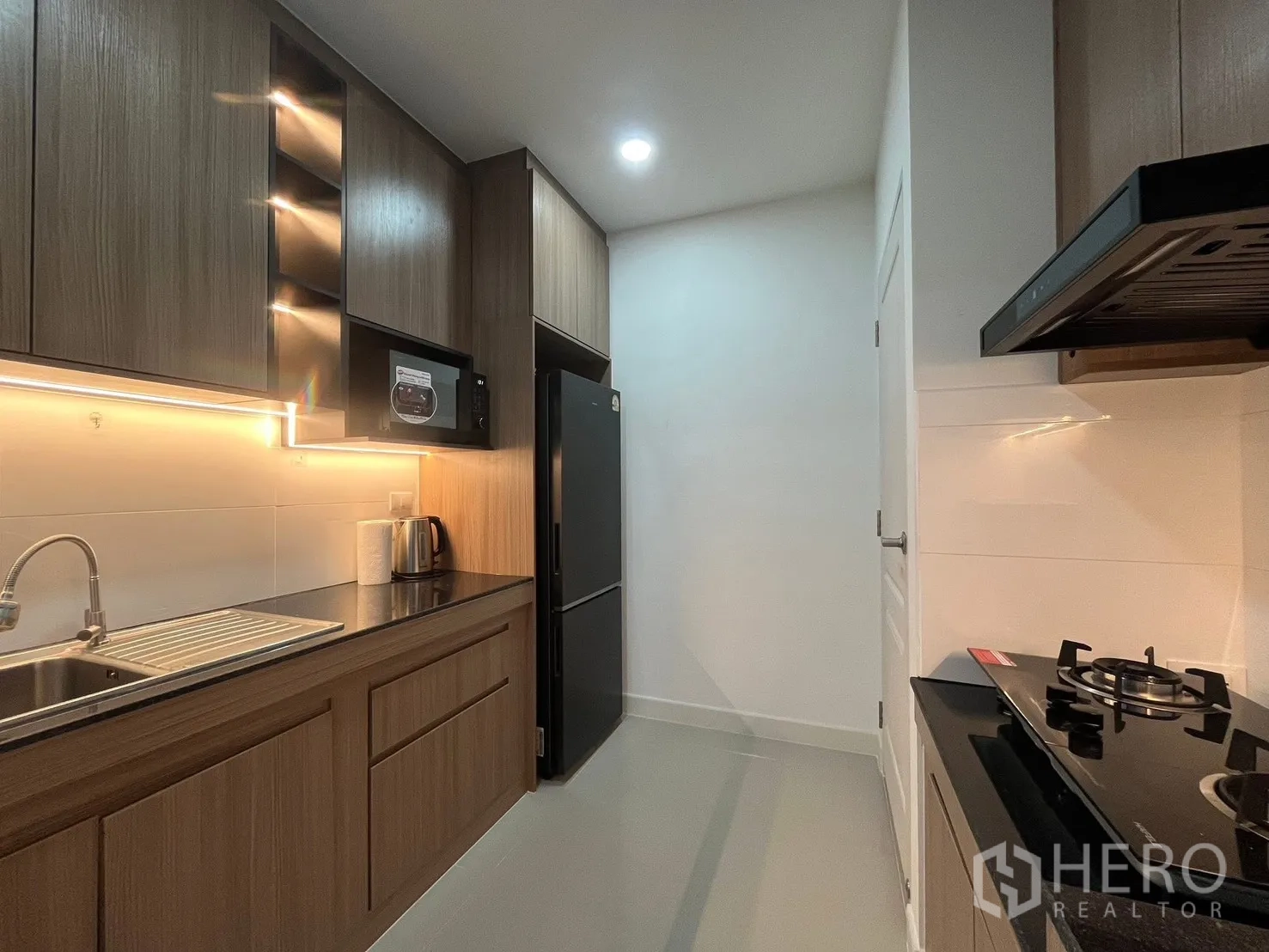Detached House for rent in Bang Phli, Samut Prakan - Galley kitchen view with refrigerator, microwave, under-cabinet lighting, and ample storage.