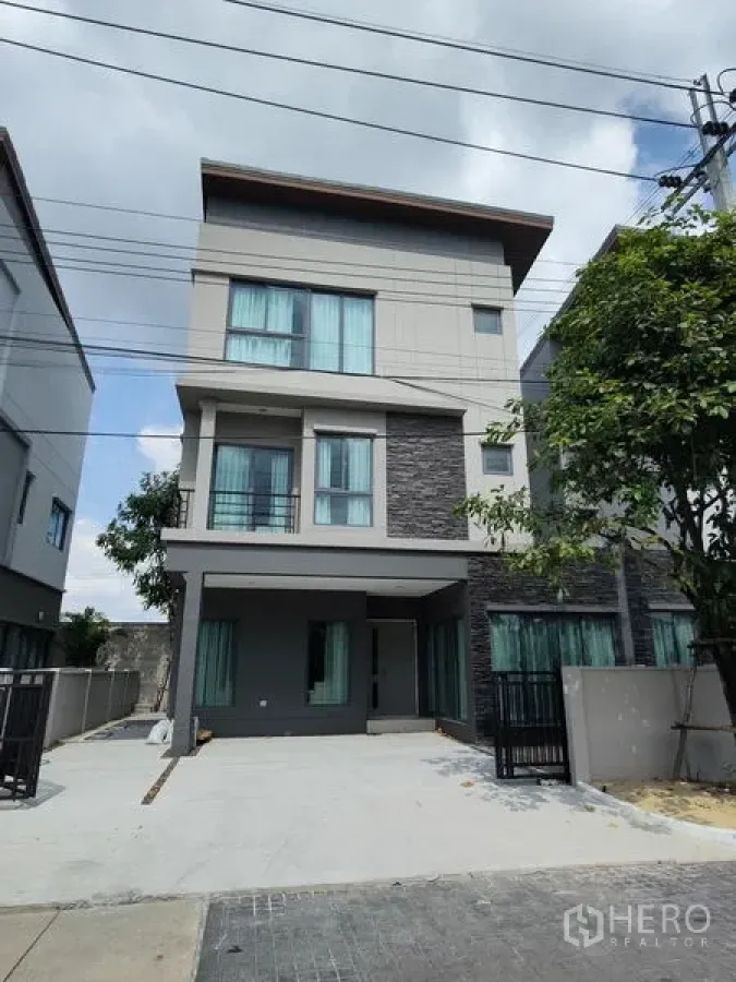 Detached House for rent in Saphan Sung, Bangkok - Modern three-storey detached house exterior with driveway, balconies and gated entrance.