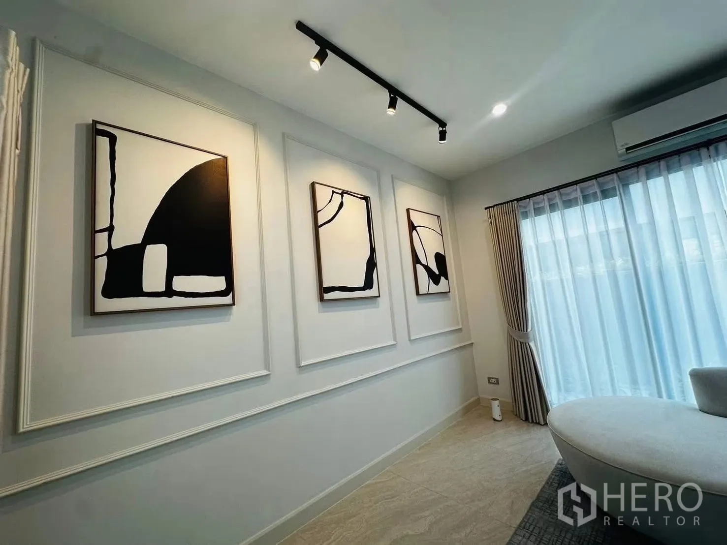 联排别墅 for rent in Suan Luang, Bangkok - 客厅一角，墙面线条装饰与抽象画，配纱帘。