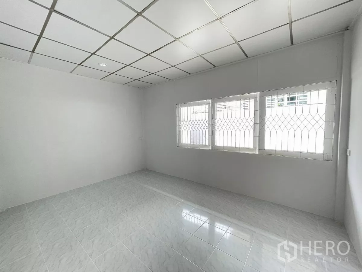 Home Office for rent in Din Daeng, Bangkok - Ground‑floor room with glossy white floor tiles and gridded security windows, ideal as an office.