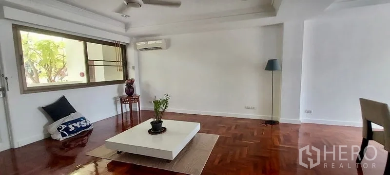 联排别墅 出租在Sathon, Bangkok - 极简客厅，矮茶几、空调与大窗户。