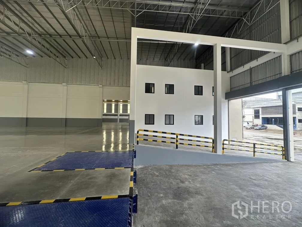 Factory for rent in Bang Phli, Samut Prakan - Blue dock levelers and safety railings beside a two-storey office structure.