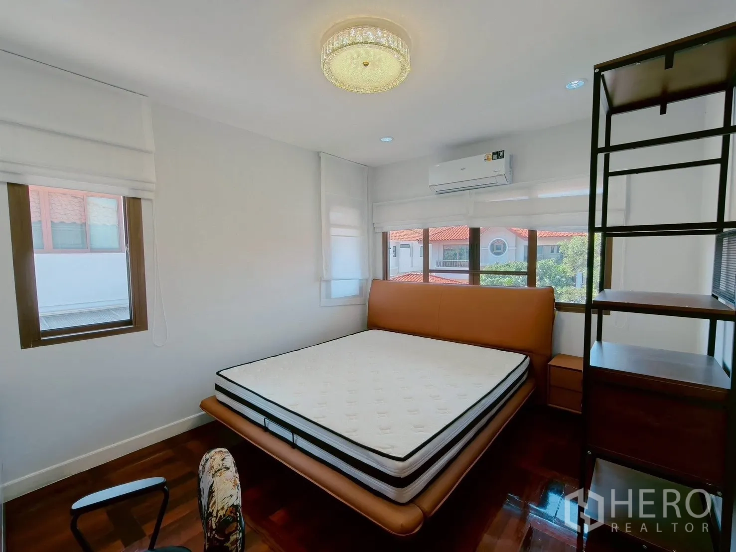 Detached House for rent in Lat Krabang, Bangkok - Corner bedroom with queen bed, wraparound windows, AC and open shelving.