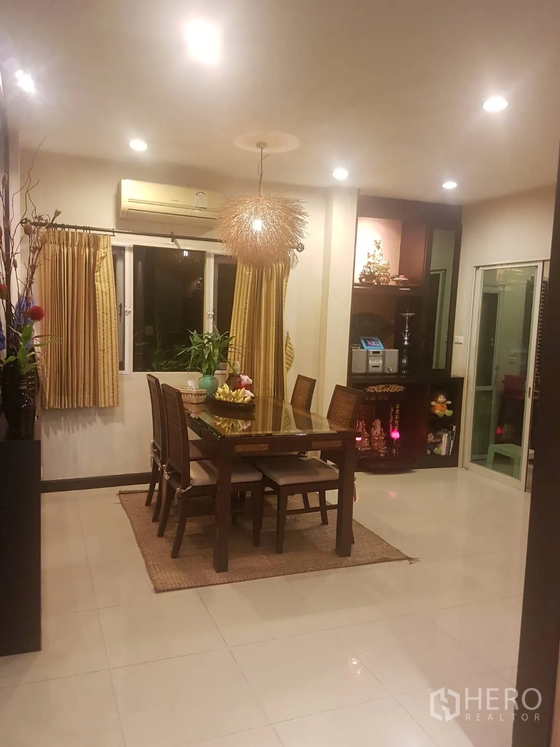 Detached House for sale in Lat Krabang, Bangkok - Bright dining room with wooden table, pendant light, tiled floors and curtained windows.