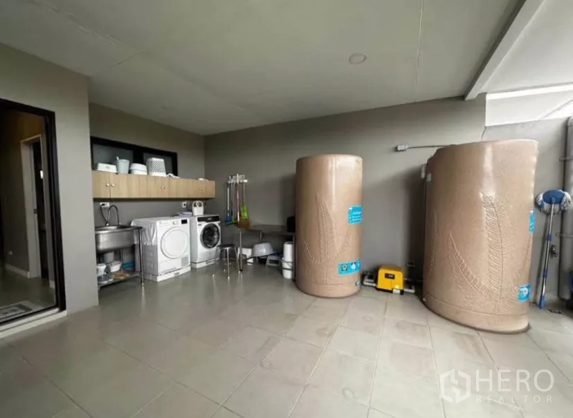 Townhouse for rent in Yan Nawa, Bangkok - Covered laundry terrace with washer, dryer, sink, and twin water tanks.