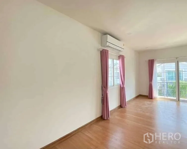 Detached House for sale in Bang Khen, Bangkok - Master bedroom with balcony access, wood floors, AC and pink curtains.