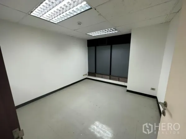 Office Space for rent in Khlong Toei, Bangkok - Private office room with fluorescent lighting and a tinted window.