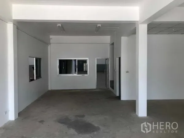 โรงงาน ให้เช่าในKhlong Luang, Pathum Thani - โถงออฟฟิศชั้นล่าง ผนังสีขาว มีหน้าต่าง และพื้นคอนกรีตภายในโรงงาน