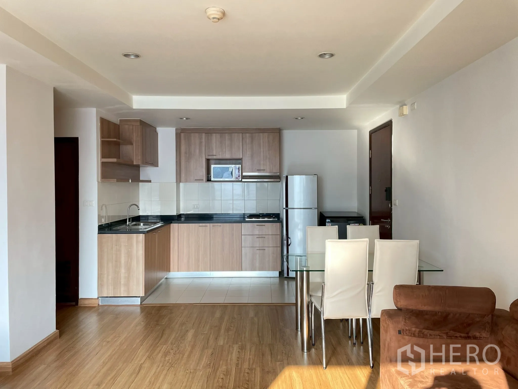 อพาร์ทเมนท์ for rent in Khlong Toei, Bangkok - ครัวแบบเปิดตู้ไม้ ตู้เย็น ไมโครเวฟ พร้อมโต๊ะทานอาหารกระจกและเก้าอี้