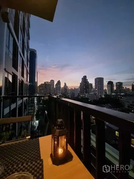 คอนโด ให้เช่าในWatthana, Bangkok - ระเบียงยามเย็นพร้อมตะเกียงและวิวสกายไลน์สุขุมวิทแบบพาโนรามา