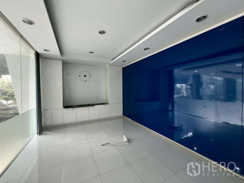 Showroom for rent - Meeting room with a blue feature wall, recessed lighting, and glass partition.