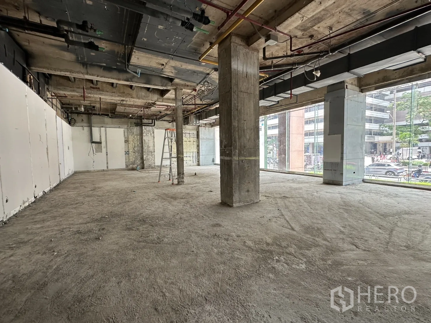 零售空间 for rent in Watthana, Bangkok - 宽大零售楼层，层高充裕，长条玻璃立面俯瞰繁忙道路。
