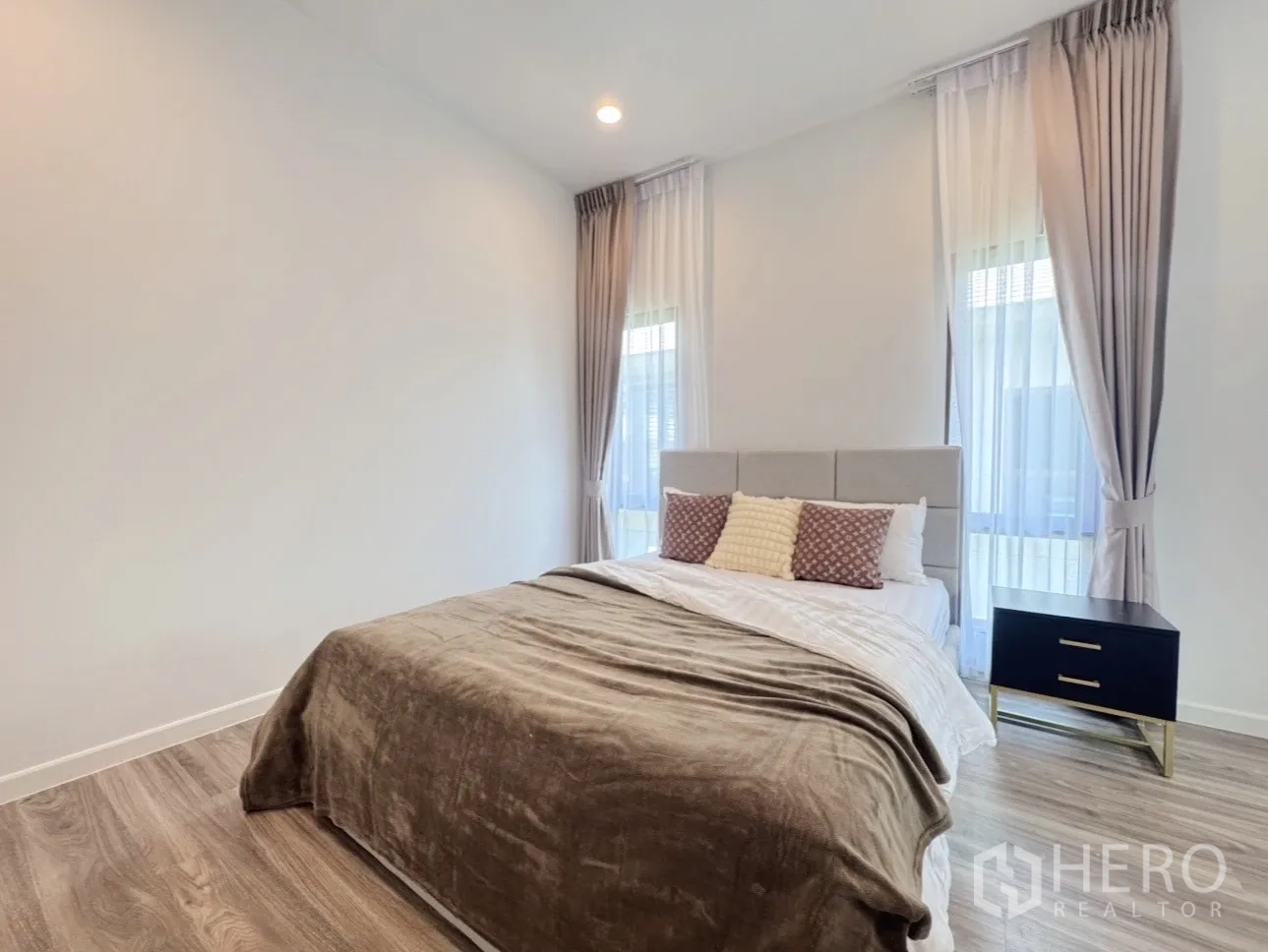 Detached House for rent or sale in Bang Kapi, Bangkok - Guest bedroom corner view with bedside table and soft window drapes.