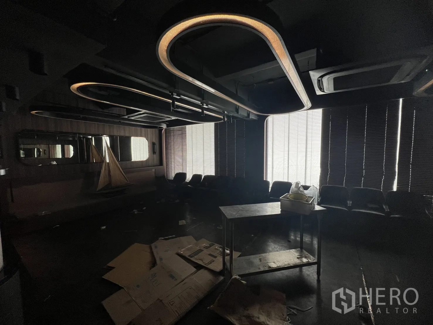 Shophouse for rent in Watthana, Bangkok - Alternate view of lounge showing curved ceiling lights and tall window blinds.