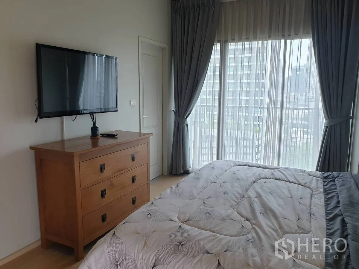公寓 出租或出售在Bangkok - 卧室内挂墙电视与全落地纱帘，眺望城市景色。