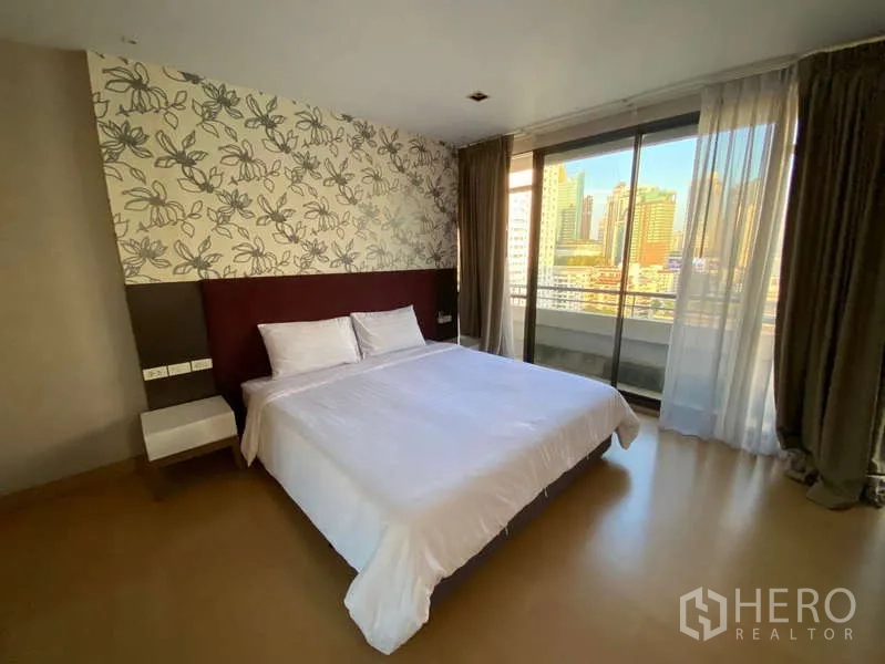 Condominium for rent in Khlong Toei, Bangkok - Second bedroom with king bed and floor-to-ceiling sliding doors to a balcony overlooking the skyline.