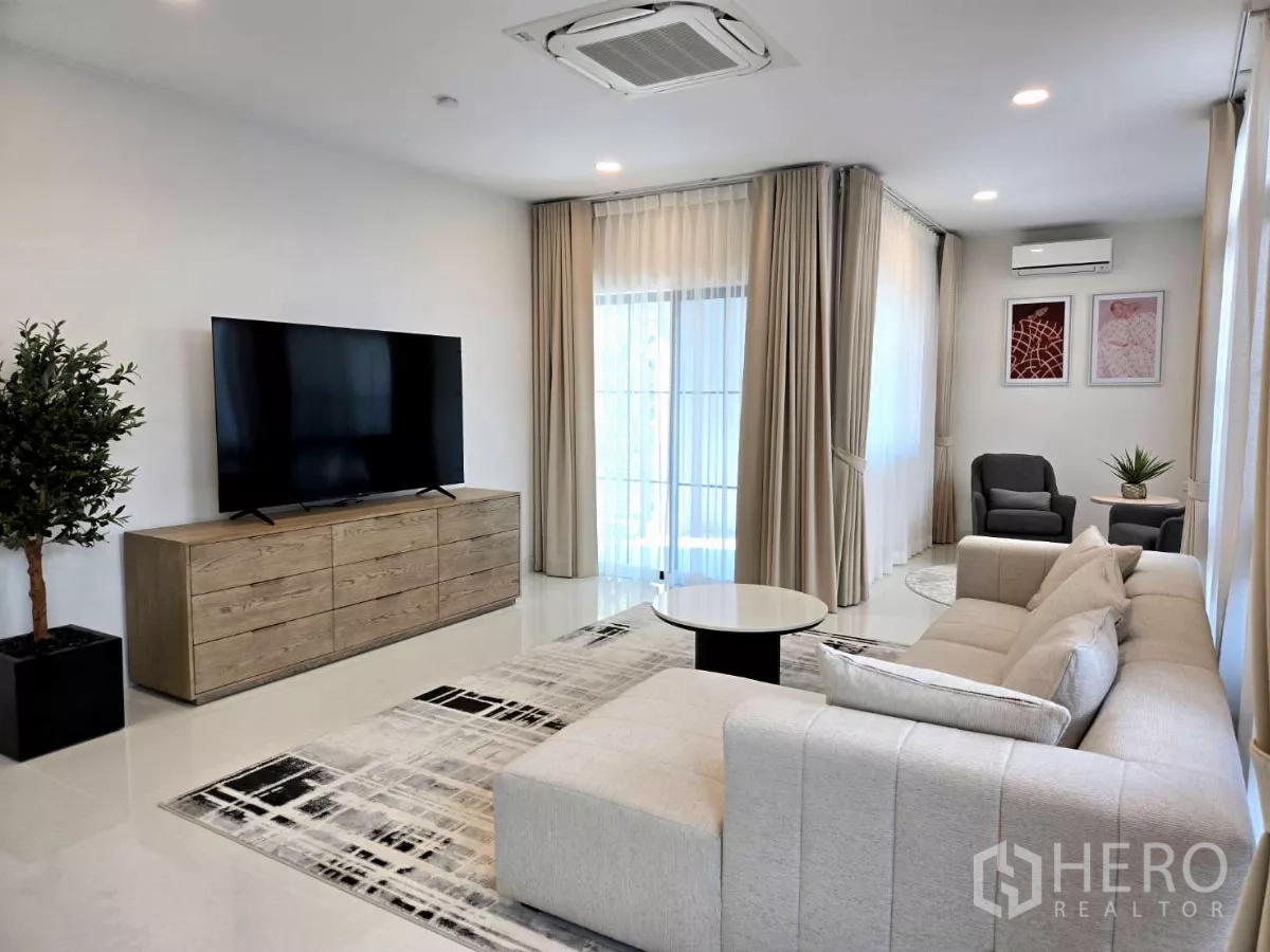 独立式住宅 出租在Saphan Sung, Bangkok - 客厅配大电视柜、转角休闲区与落地窗帘。