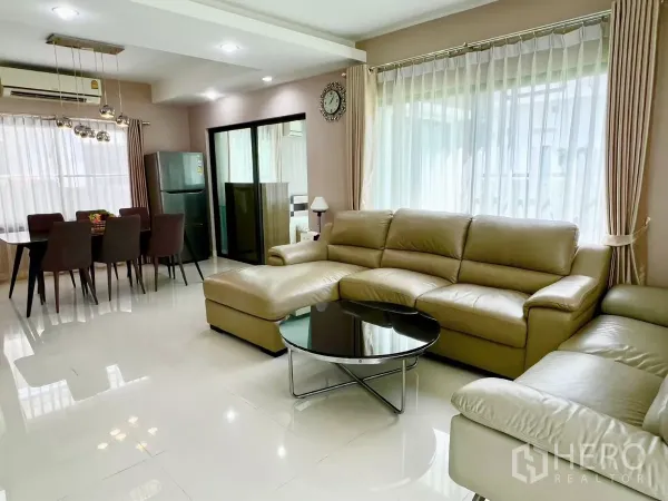 บ้าน ให้เช่าหรือขายในBang Phli, Samut Prakan - โถงนั่งเล่นและทานอาหารแบบโอเพ่นแปลน พร้อมโซฟาหนังและหน้าต่างบานใหญ่.