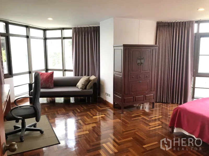Condominium for rent or sale in Watthana, Bangkok - Master bedroom work and sitting area with desk, sofa and wide windows.