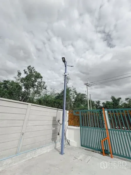 货栈 出租或出售在Khlong Luang, Pathum Thani - 入口近景，金属推拉门、庭院路灯与供电设施。