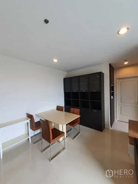Condominium for sale - Dining area with a table for four and a large black storage cabinet.