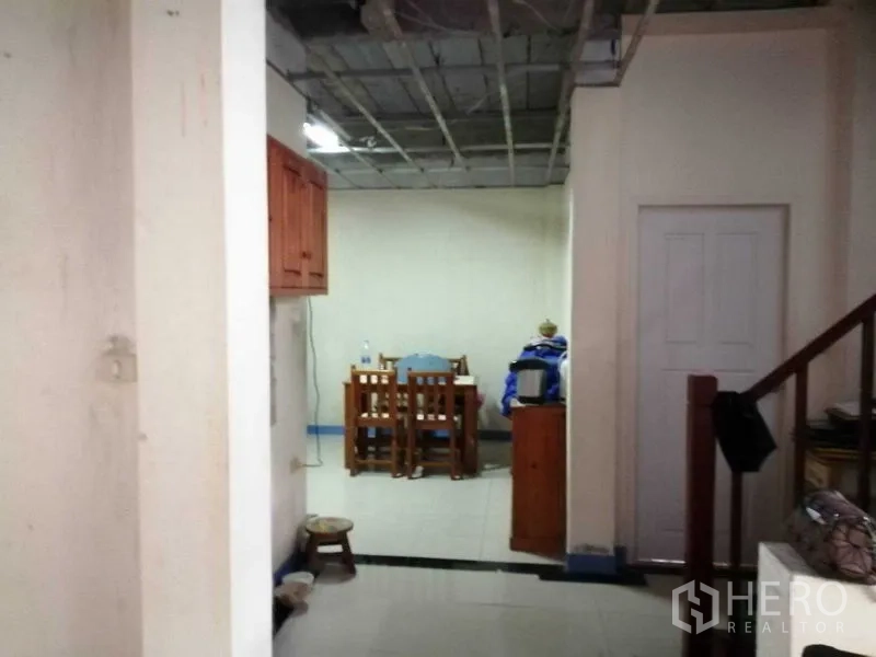 独立式住宅 出售在Prawet, Bangkok - 用餐区与走廊，瓷砖地面、楼梯与部分敞开的天花板。