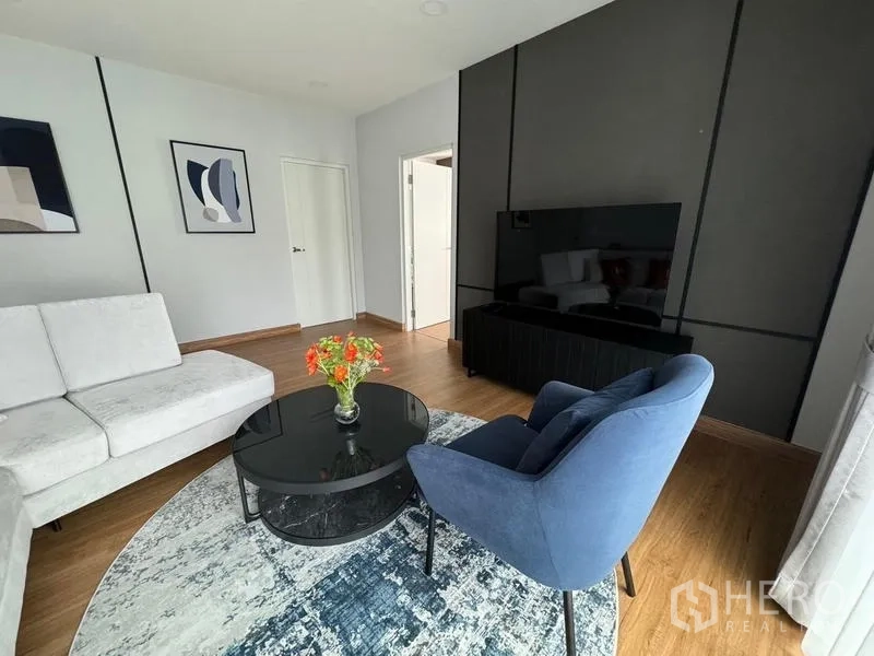 Detached House for rent or sale in Bang Phli, Samut Prakan - Cozy TV corner with navy armchair, round glass coffee table and patterned rug.
