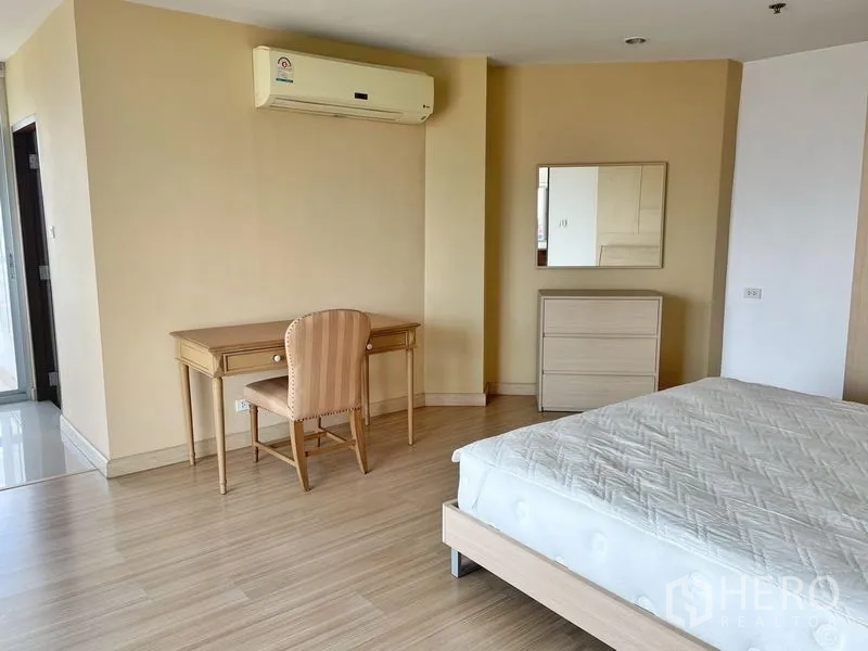 Condominium for rent in Khlong Toei, Bangkok - Bedroom corner with writing desk, chest of drawers and wall-mounted air conditioner.
