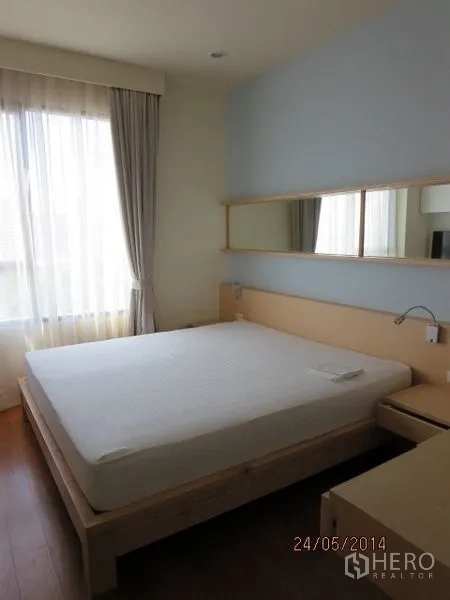 Condominium for rent in Bang Rak, Bangkok - Bright bedroom with a large window, light wood bed frame and neutral tones.