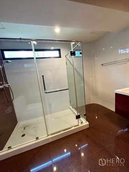 Condominium for rent in Bangkok - Close-up of walk-in shower with glass doors and handheld shower.