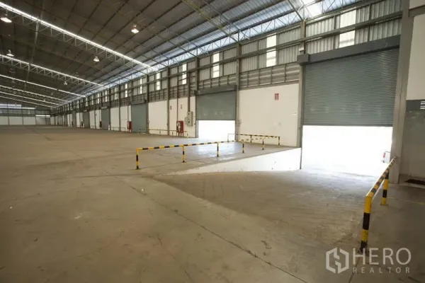 Warehouse for rent in Si Racha, Chon Buri - Loading bay with drive-in ramps and multiple roller shutter doors inside the warehouse.