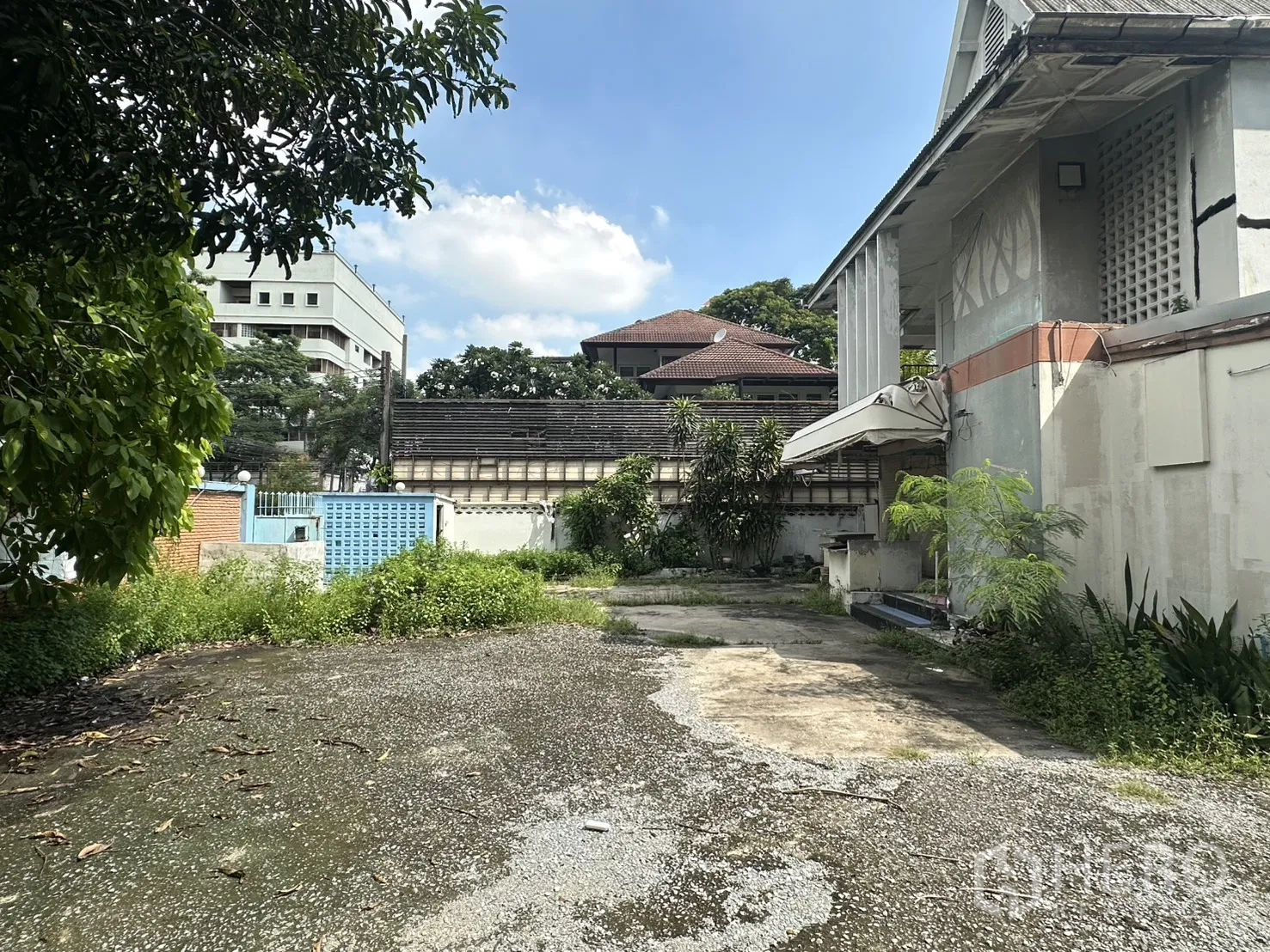 独栋房屋 for rent in Watthana, Bangkok - 房屋一侧的碎石车道与开放庭院，周边楼宇环绕。
