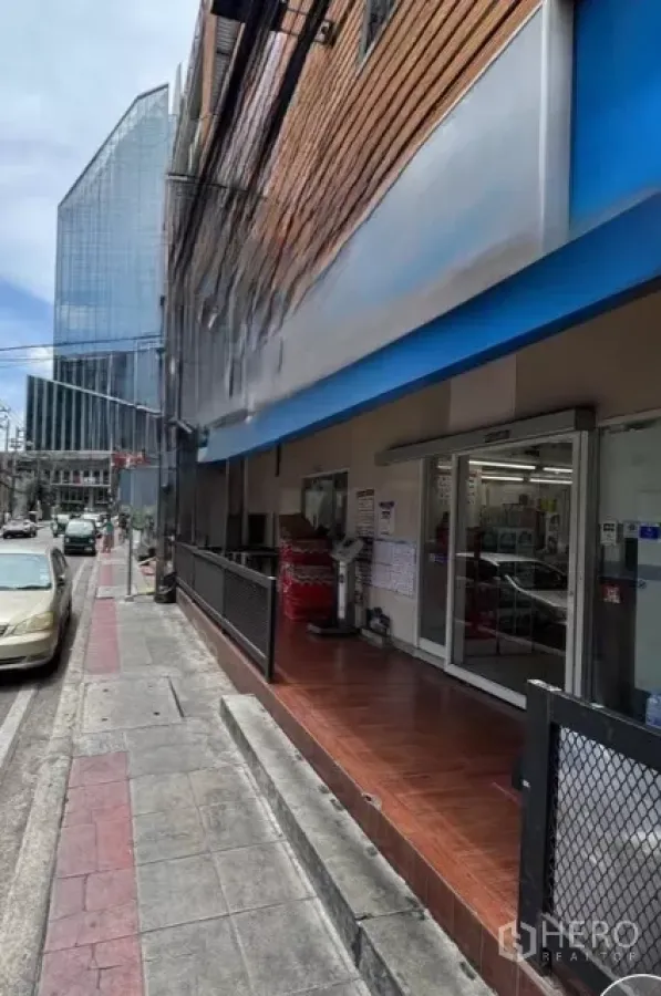 Retail Space for rent in Watthana, Bangkok - Ground-floor retail frontage with blue awning and glass entrance on a busy side street near a modern office tower in Phrom Phong.