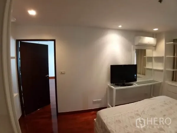 Condominium for rent or sale in Pathum Wan, Bangkok - Bedroom corner with work desk, mirror, TV and wall-mounted air conditioner.