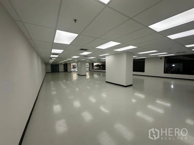 办公空间 出租在Phaya Thai, Bangkok - 宽敞开放式办公室，白墙、网格吊顶与明亮LED灯，光滑地面和结构柱。