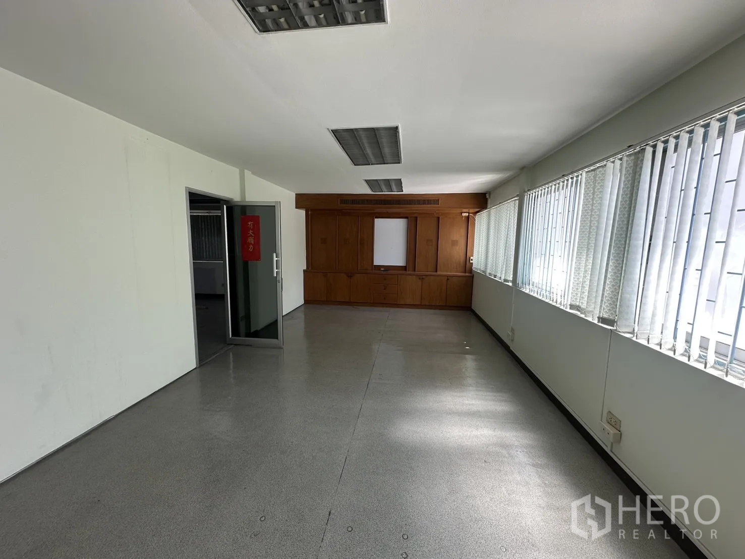 Retail Space for rent in Watthana, Bangkok - Bright room with long windows and wood built-in storage at far end.