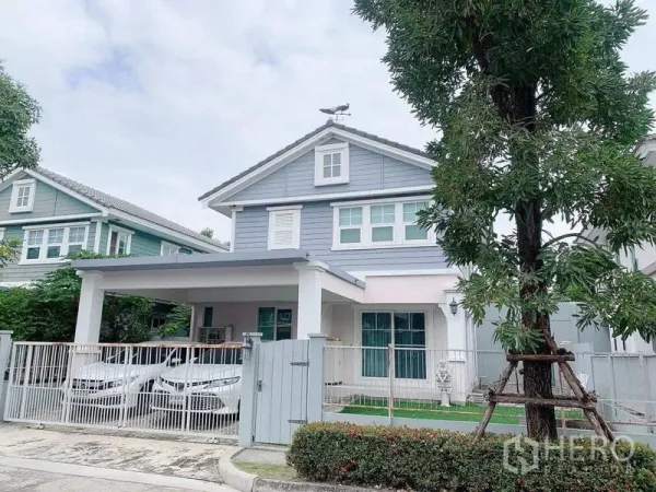 บ้าน ให้เช่าหรือขายในBang Phli, Samut Prakan - มุมหน้าบ้านอีกด้าน แสดงโรงจอดรถ 2 คันและสนามหญ้าหลังรั้วสี白