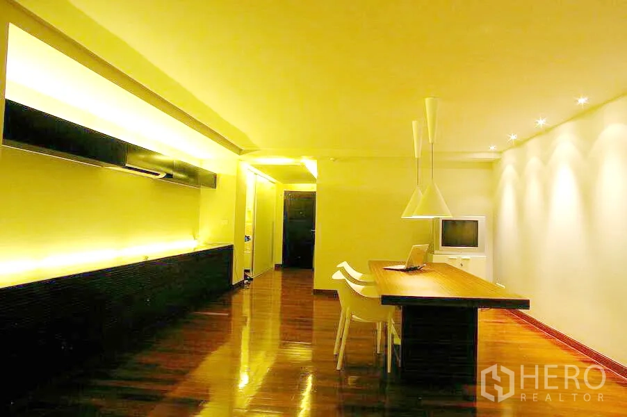 公寓 出租在Watthana, Bangkok - 用餐区设长木桌、白色餐椅、吊灯与氛围灯带。