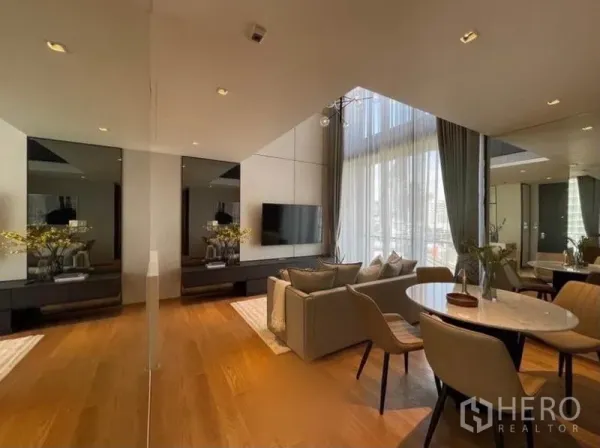Condominium for rent in Khlong Toei, Bangkok - Dining corner and sofa set with mirrored panels, wood floors and tall draped windows.