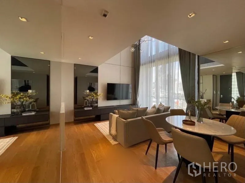 Condominium for rent in Khlong Toei, Bangkok - Dining corner and sofa set with mirrored panels, wood floors and tall draped windows.