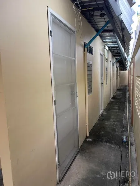 Factory for rent in Lat Lum Kaeo, Pathum Thani - Narrow exterior corridor with multiple doors and an overhead awning at the factory.