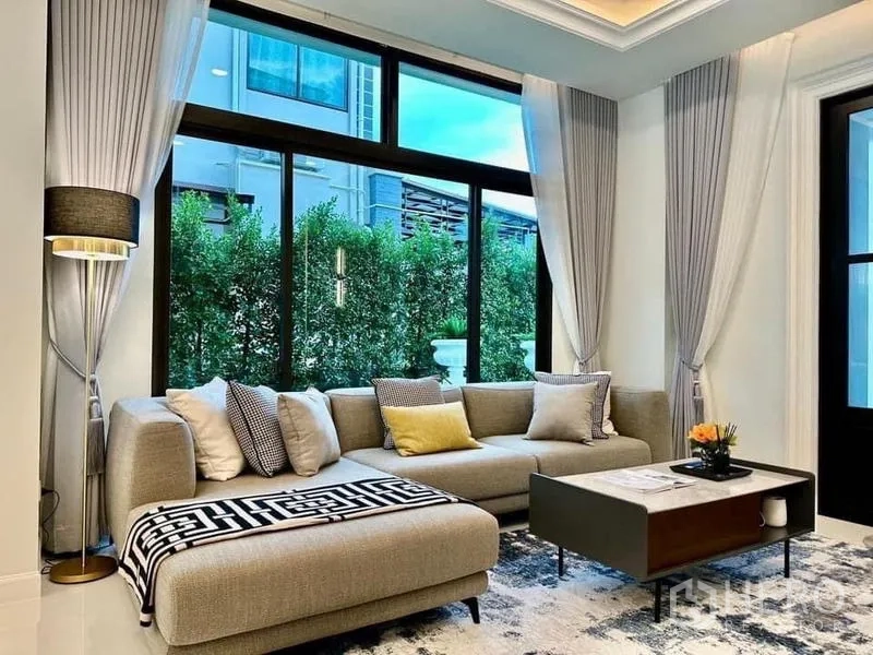 独立式住宅 出租在Lat Krabang, Bangkok - 明亮休息区，L形沙发，临近大窗与绿篱