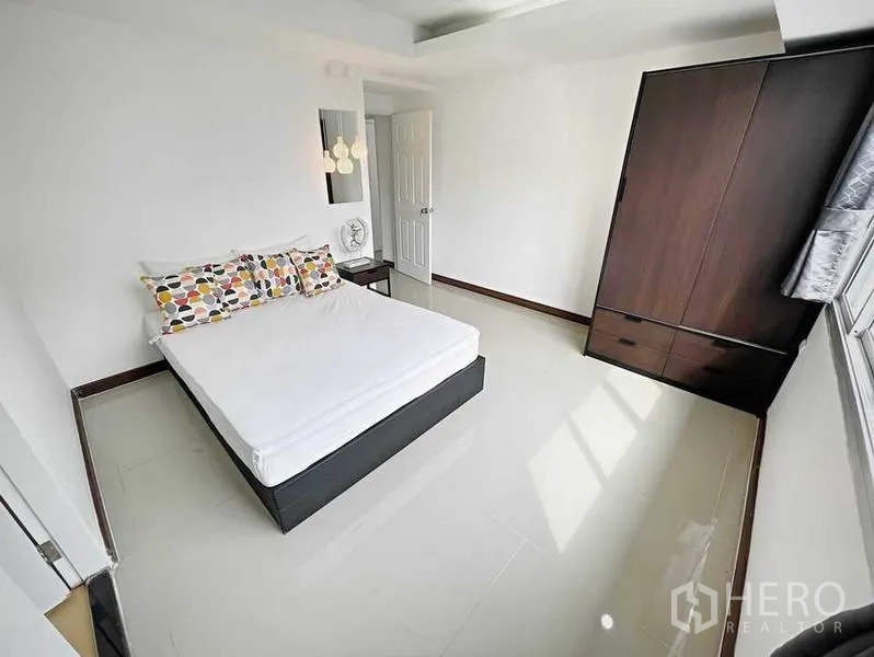 Condominium for rent in Khlong Toei, Bangkok - Second bedroom with double bed, dark wardrobe and sunlit window.