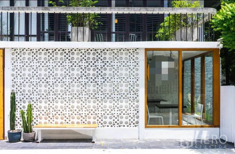 Retail Space for rent in Khlong Toei, Bangkok - Street‑facing facade with white breeze‑block feature wall, wood‑framed glass entrance, bench and potted cacti.